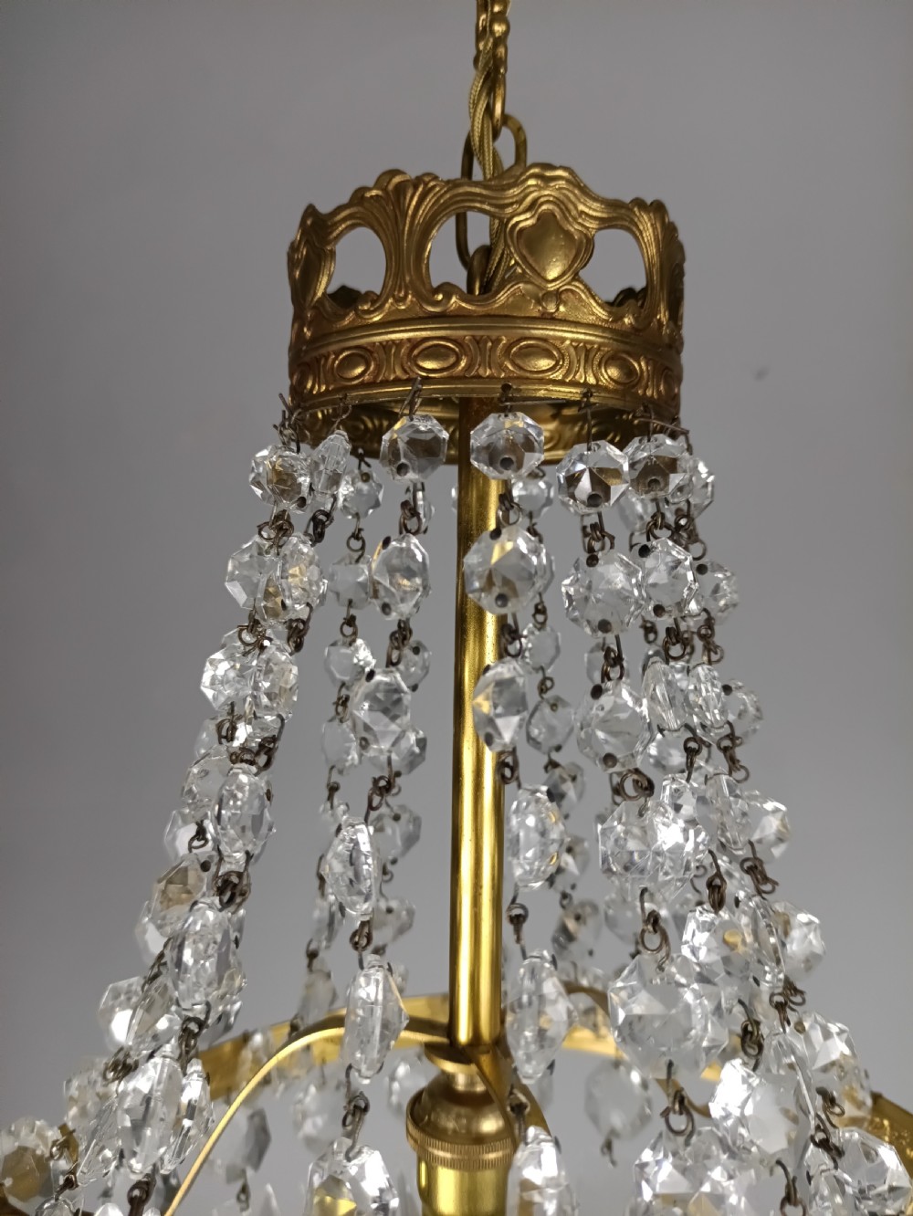 An antique French tent and bag chandelier featuring cascading crystal beads attached to a decorative brass rim with cut glass prisms below. View VI