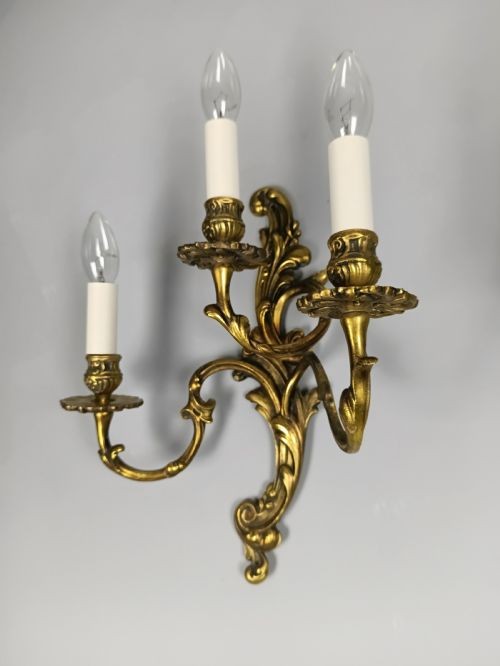 A pair of ornate gilded brass wall lights featuring three curving candle arms and Rococo scrollwork. View III