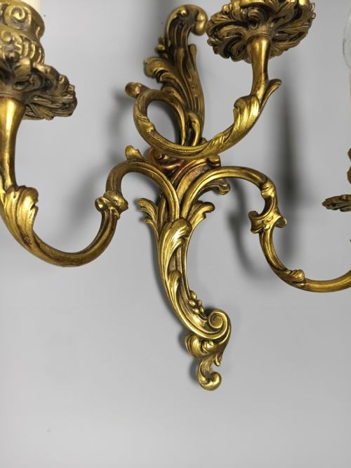 A pair of ornate gilded brass wall lights featuring three curving candle arms and Rococo scrollwork. View VI
