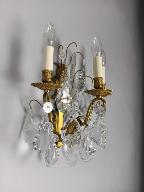 A pair of French Baroque style wall sconces featuring gilded brass frames with three arms each and hanging cut crystal drops. View II