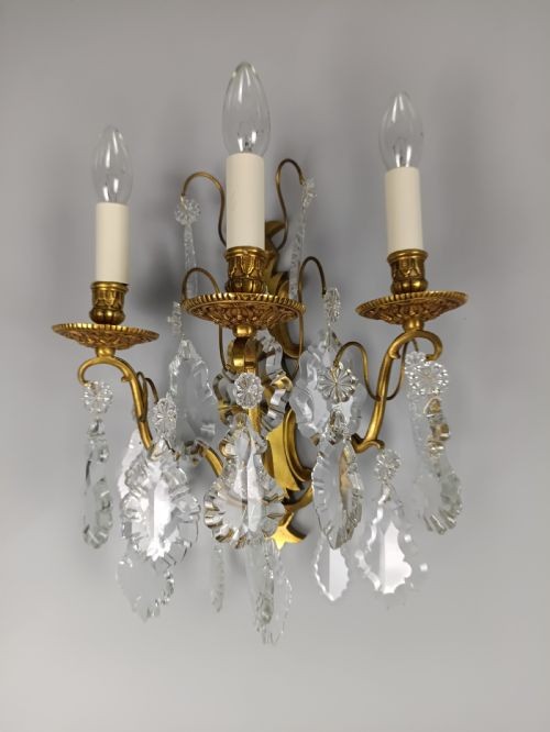 A pair of French Baroque style wall sconces featuring gilded brass frames with three arms each and hanging cut crystal drops. View III