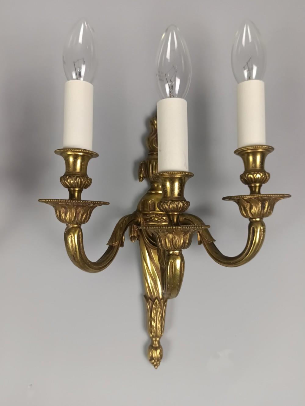 A pair of French Neoclassical gilded brass wall lights featuring three curving candle arms attached to a central tapered, fluted backplate. View III