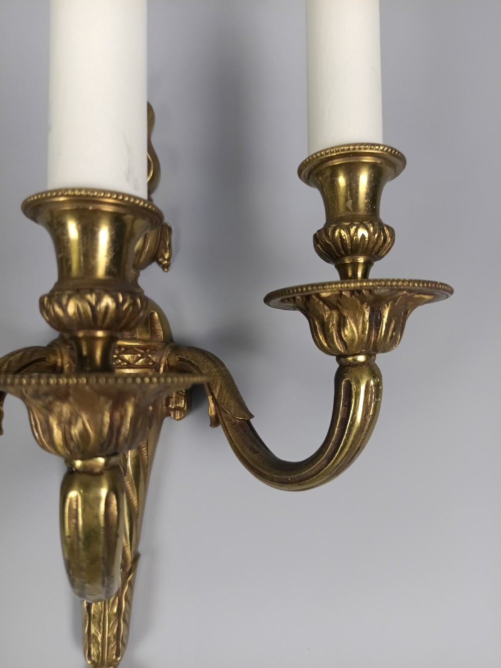 A pair of French Neoclassical gilded brass wall lights featuring three curving candle arms attached to a central tapered, fluted backplate. View VII