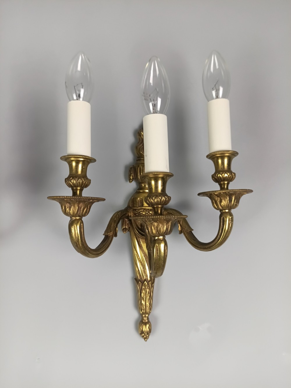 A pair of French Neoclassical gilded brass wall lights featuring three curving candle arms attached to a central tapered, fluted backplate. View XI