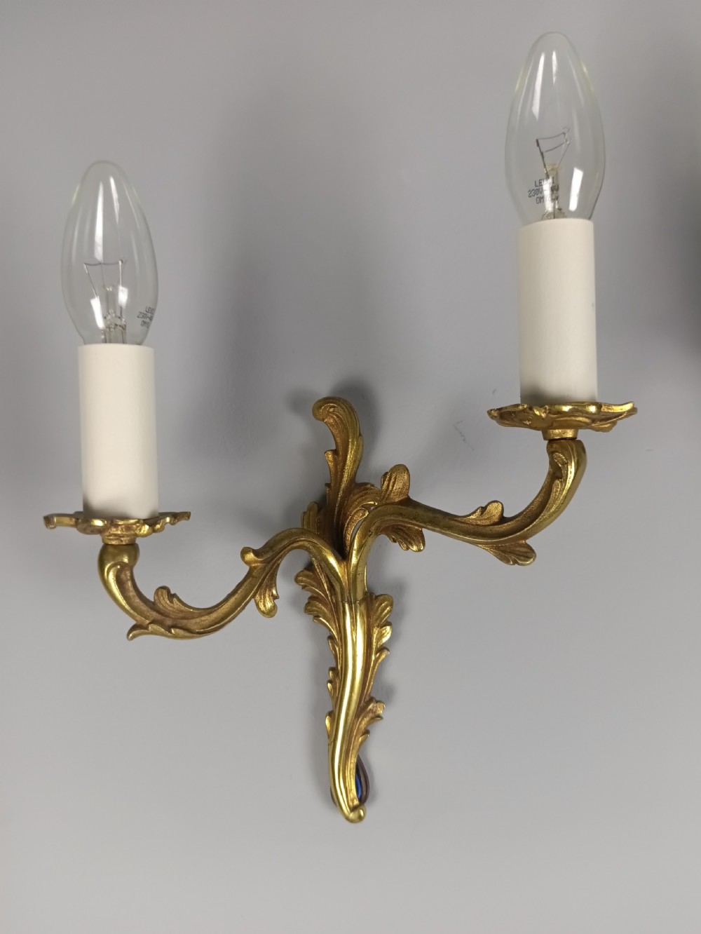 A pair of French gilt brass two-arm wall sconces featuring acanthus leaf scrollwork and candle-style bulb holders. View II