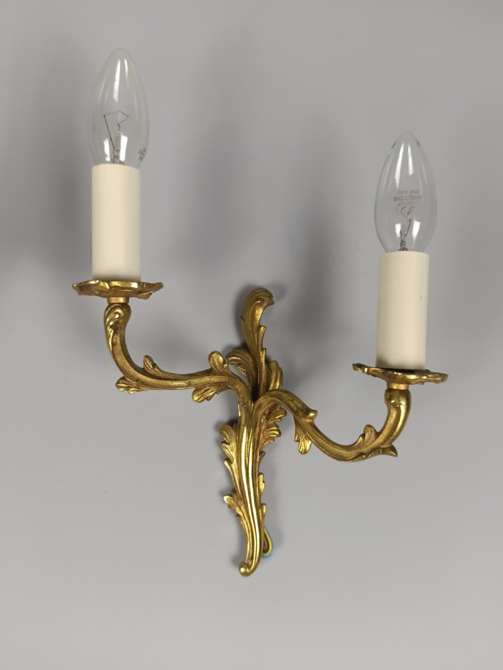 A pair of French gilt brass two-arm wall sconces featuring acanthus leaf scrollwork and candle-style bulb holders. View IV