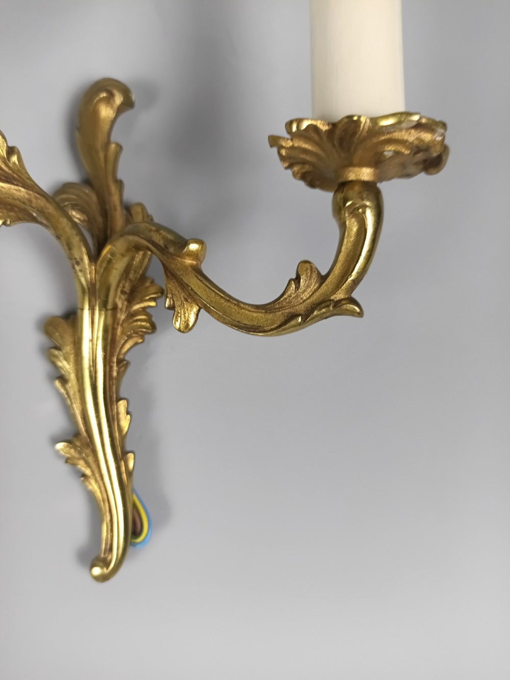A pair of French gilt brass two-arm wall sconces featuring acanthus leaf scrollwork and candle-style bulb holders. View V