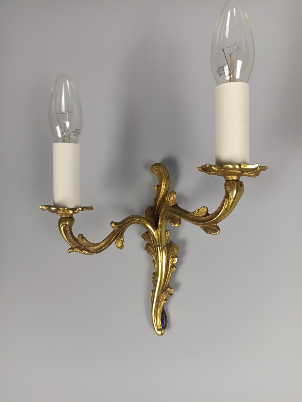 A pair of French gilt brass two-arm wall sconces featuring acanthus leaf scrollwork and candle-style bulb holders. View VI