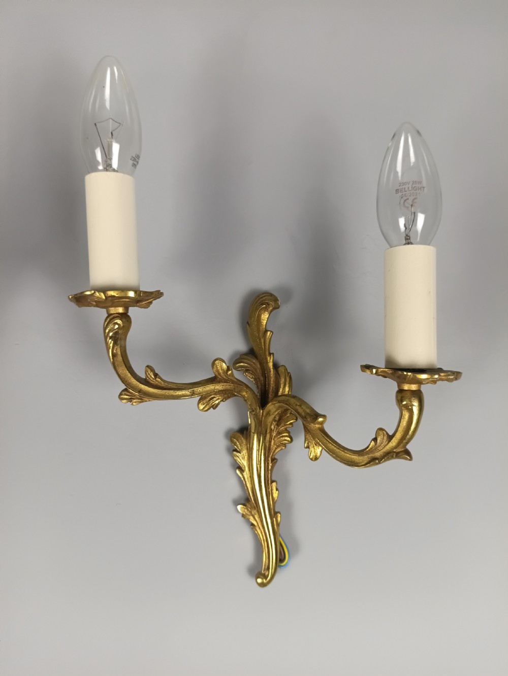 A pair of French gilt brass two-arm wall sconces featuring acanthus leaf scrollwork and candle-style bulb holders. View VII