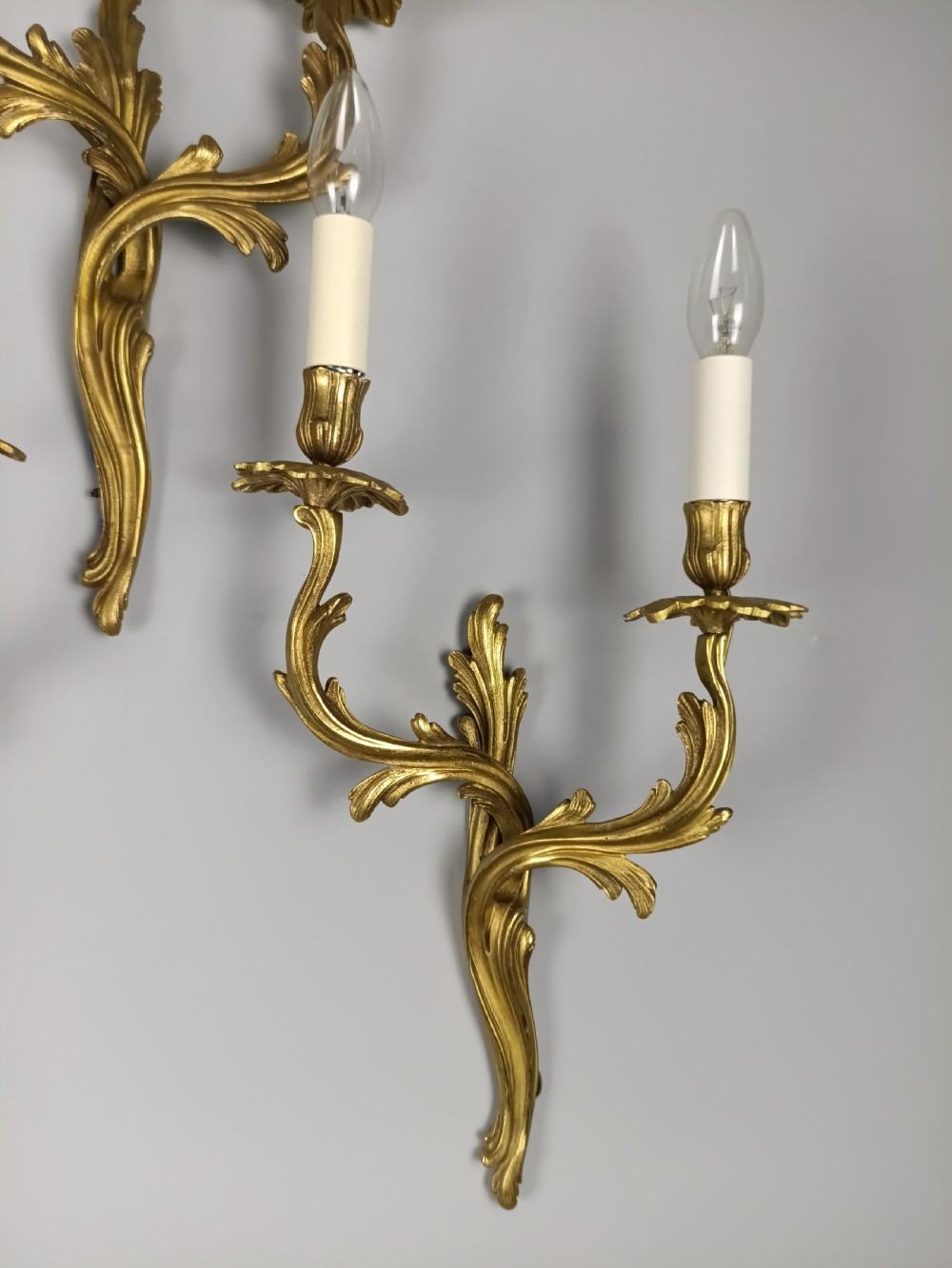 Set of four French Rococo style gilt brass twin-arm wall sconces featuring acanthus leaf motifs. View V
