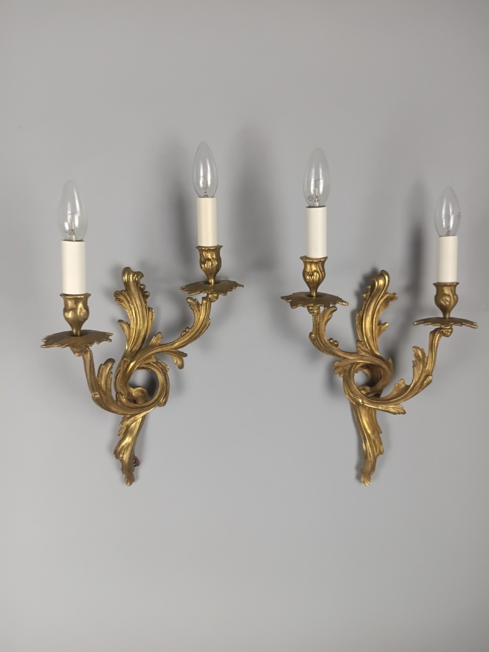 A pair of French Rococo style gilded bronze wall sconces with twin scrolling acanthus arms and candle sleeves. View II