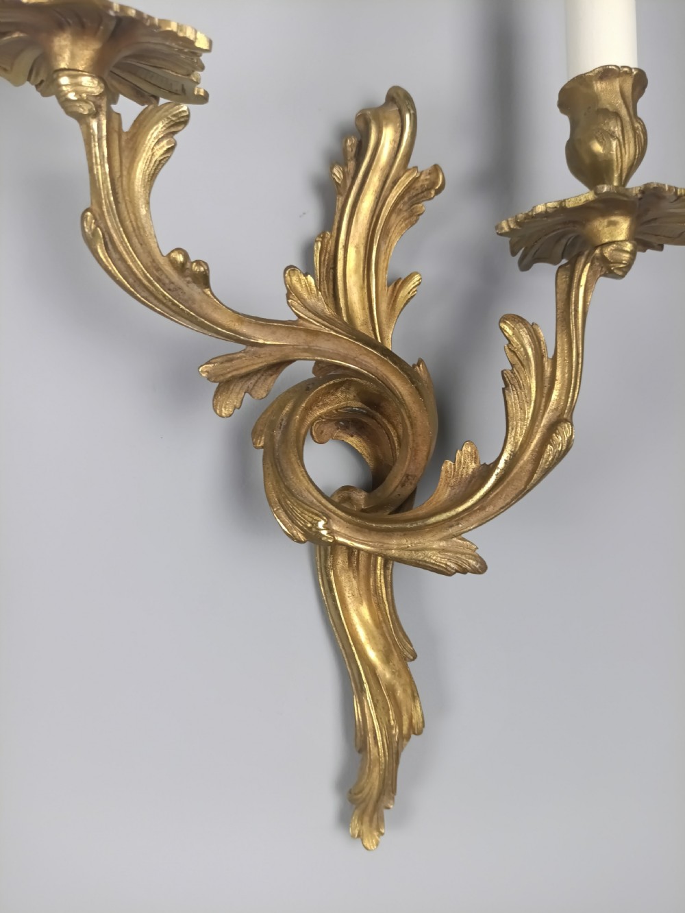 A pair of French Rococo style gilded bronze wall sconces with twin scrolling acanthus arms and candle sleeves. View IV