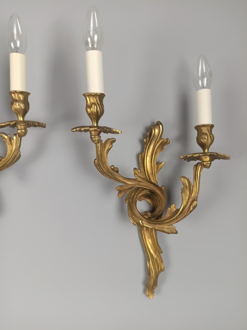 A pair of French Rococo style gilded bronze wall sconces with twin scrolling acanthus arms and candle sleeves. View VI