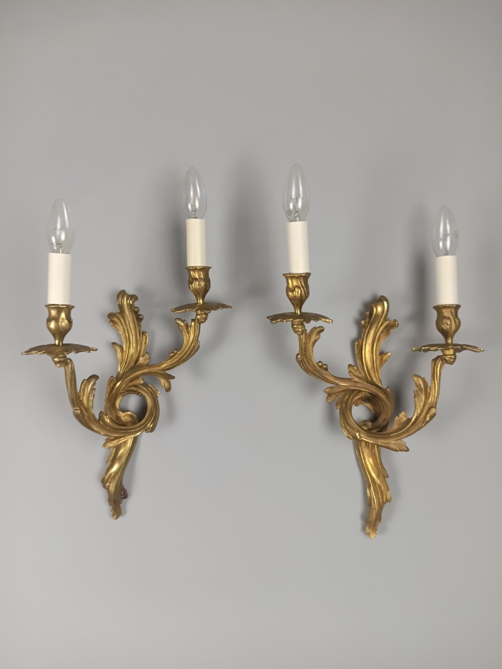 A pair of French Rococo style gilded bronze wall sconces with twin scrolling acanthus arms and candle sleeves. View VII