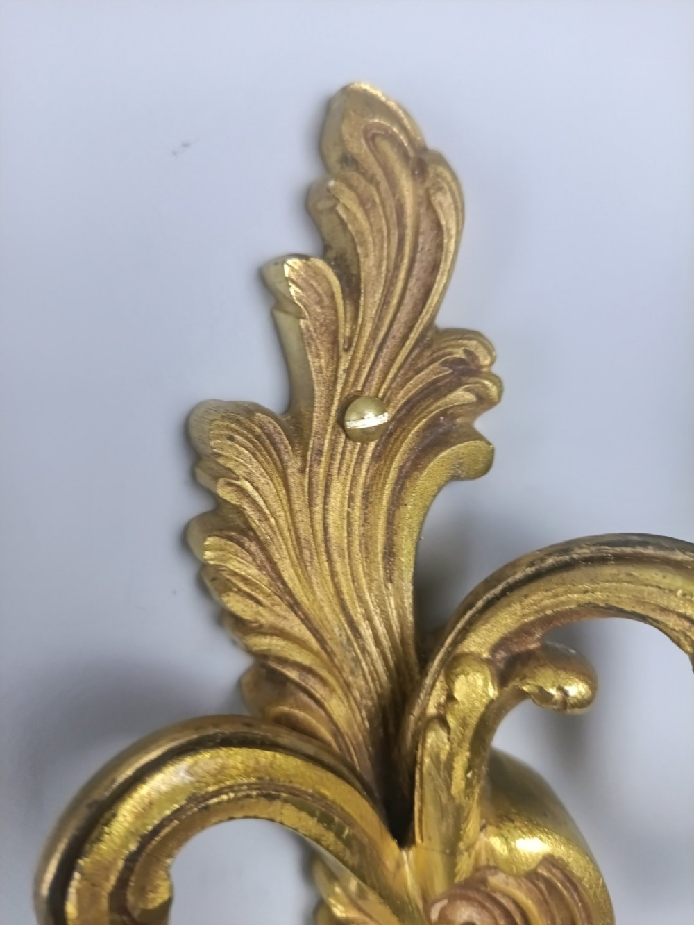 A pair of antique French Rococo gilded bronze twin-arm wall sconces featuring ornate acanthus leaf scrolling and candle sockets. View IV