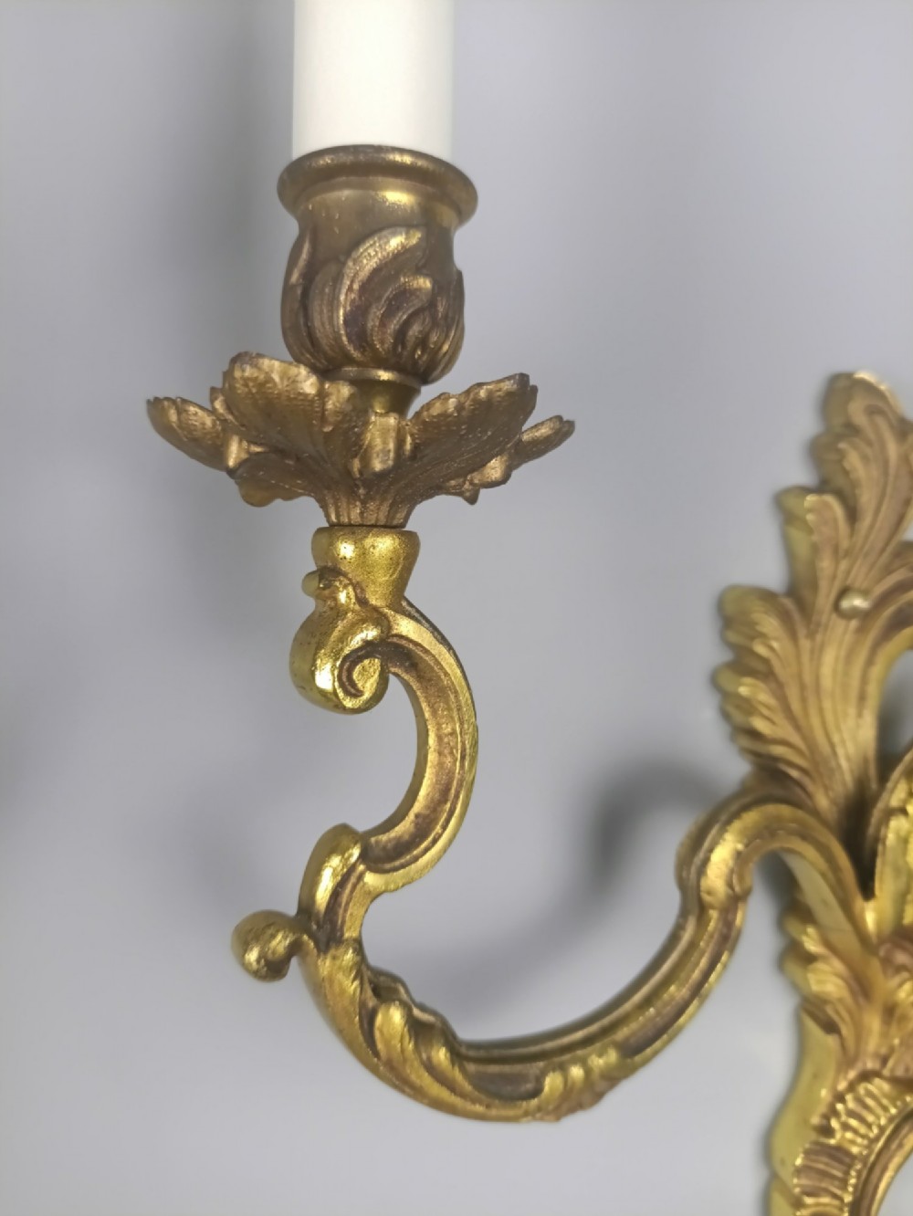 A pair of antique French Rococo gilded bronze twin-arm wall sconces featuring ornate acanthus leaf scrolling and candle sockets. View V