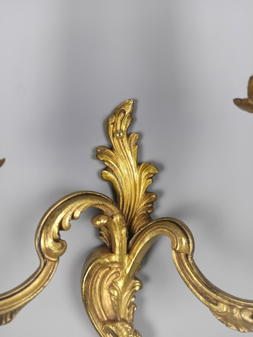 A pair of antique French Rococo gilded bronze twin-arm wall sconces featuring acanthus leaf motifs and candle sleeve light fixtures. View III