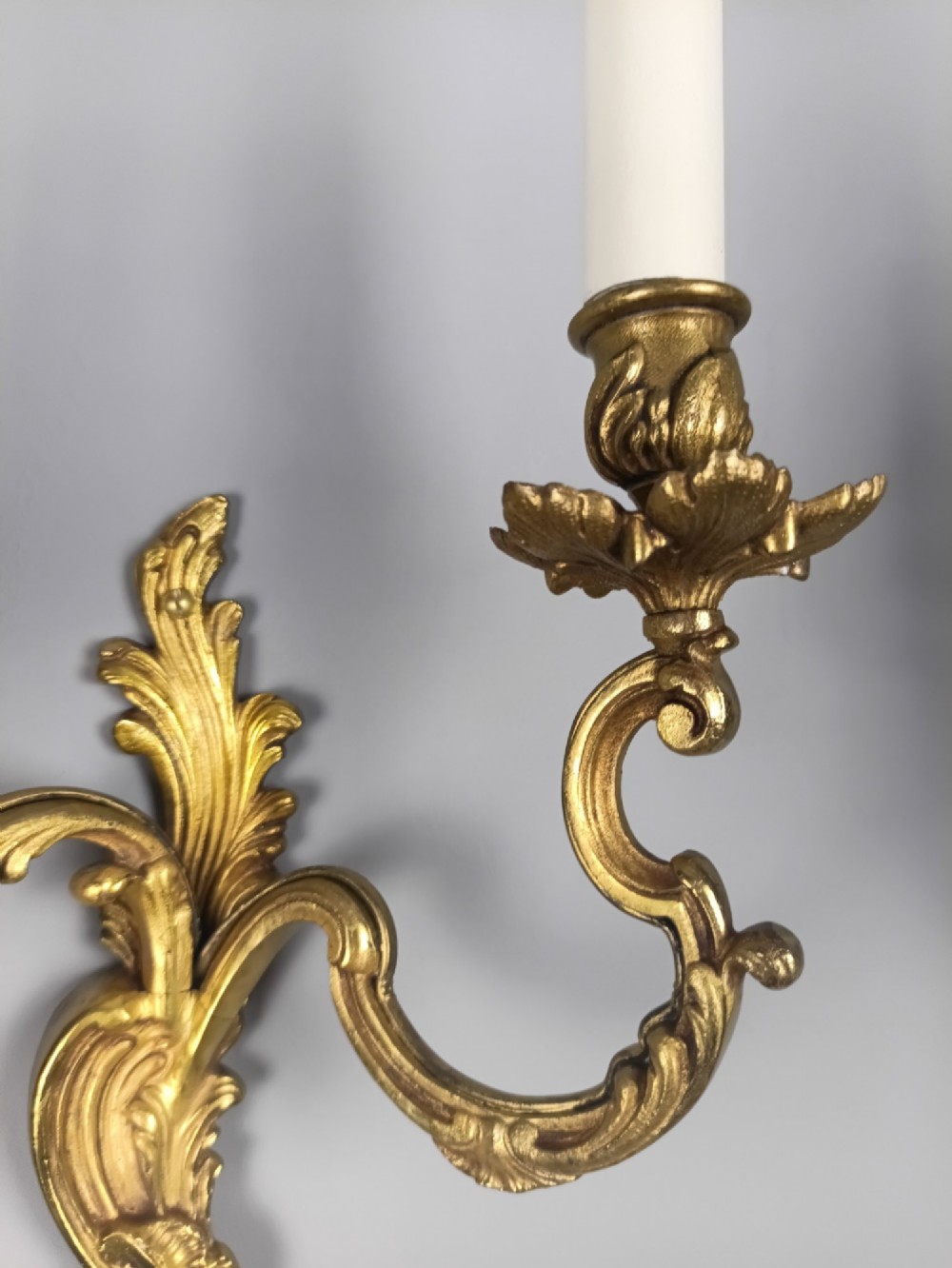 A pair of antique French Rococo gilded bronze twin-arm wall sconces featuring acanthus leaf motifs and candle sleeve light fixtures. View IV