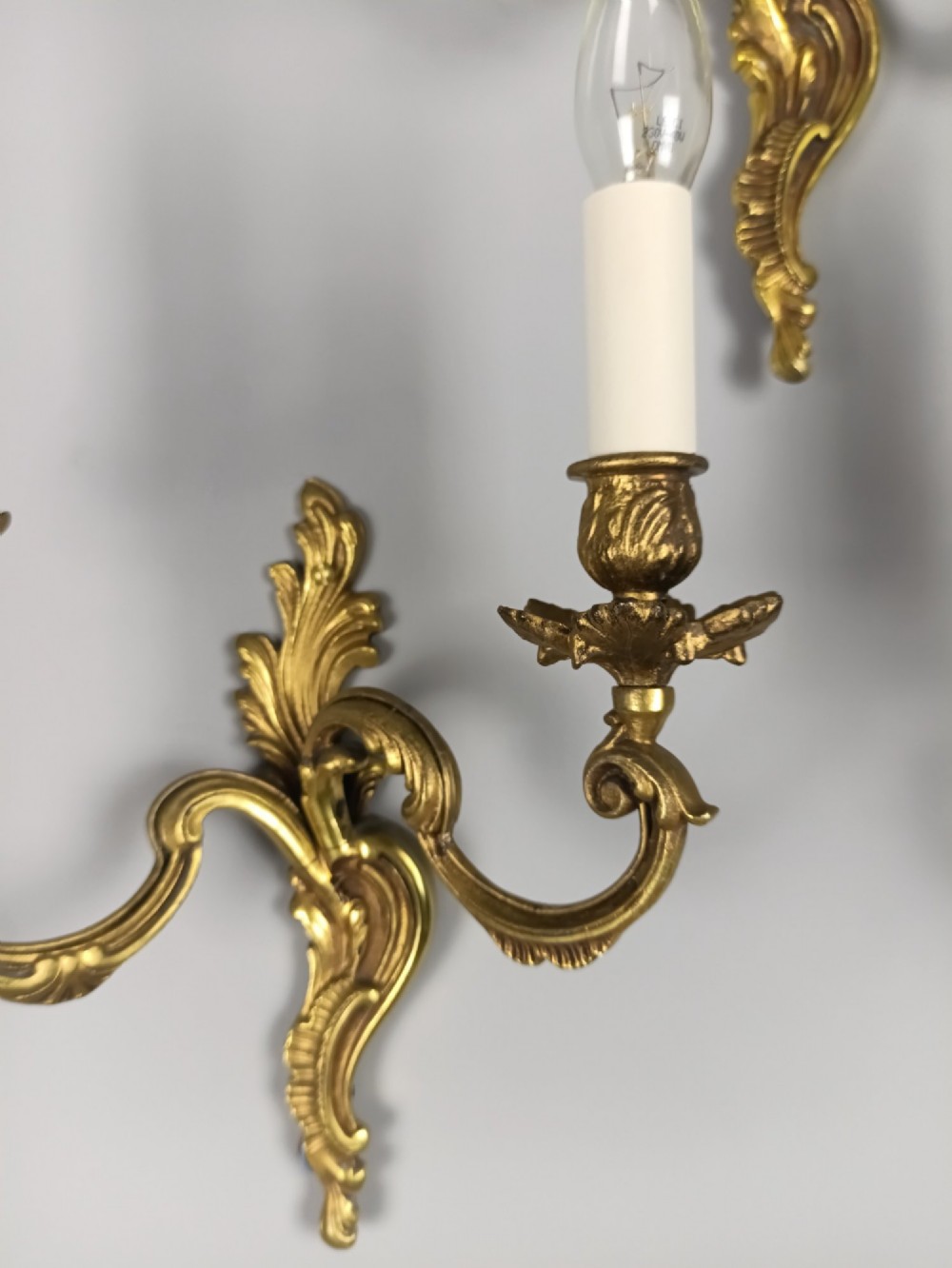A set of three French antique gilded bronze twin-arm wall sconces featuring acanthus leaf scrolling motifs and candle sleeves. View III