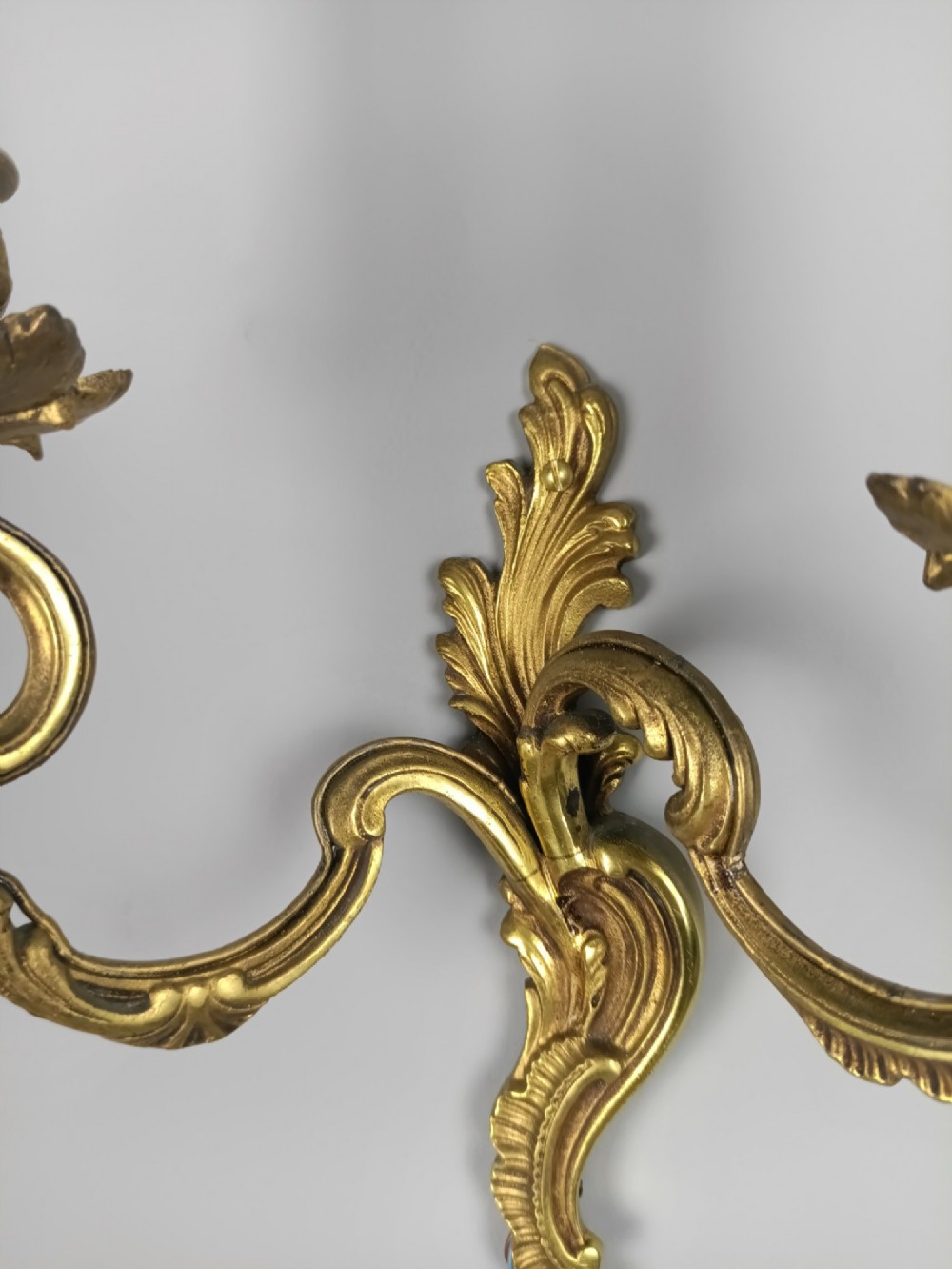 A set of three French antique gilded bronze twin-arm wall sconces featuring acanthus leaf scrolling motifs and candle sleeves. View VI