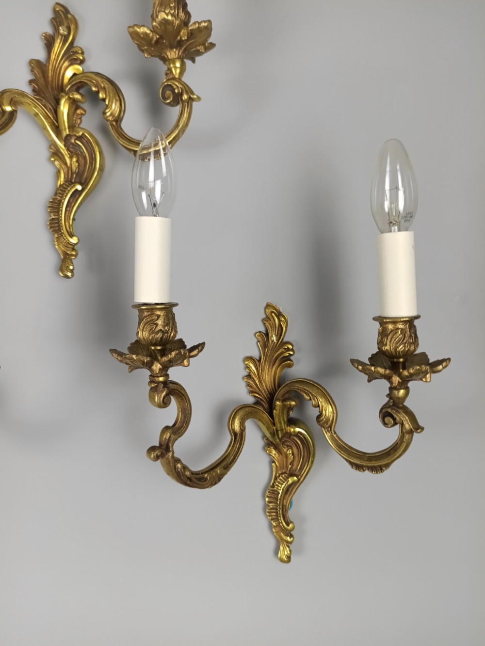 A set of three French antique gilded bronze twin-arm wall sconces featuring acanthus leaf scrolling motifs and candle sleeves. View VII