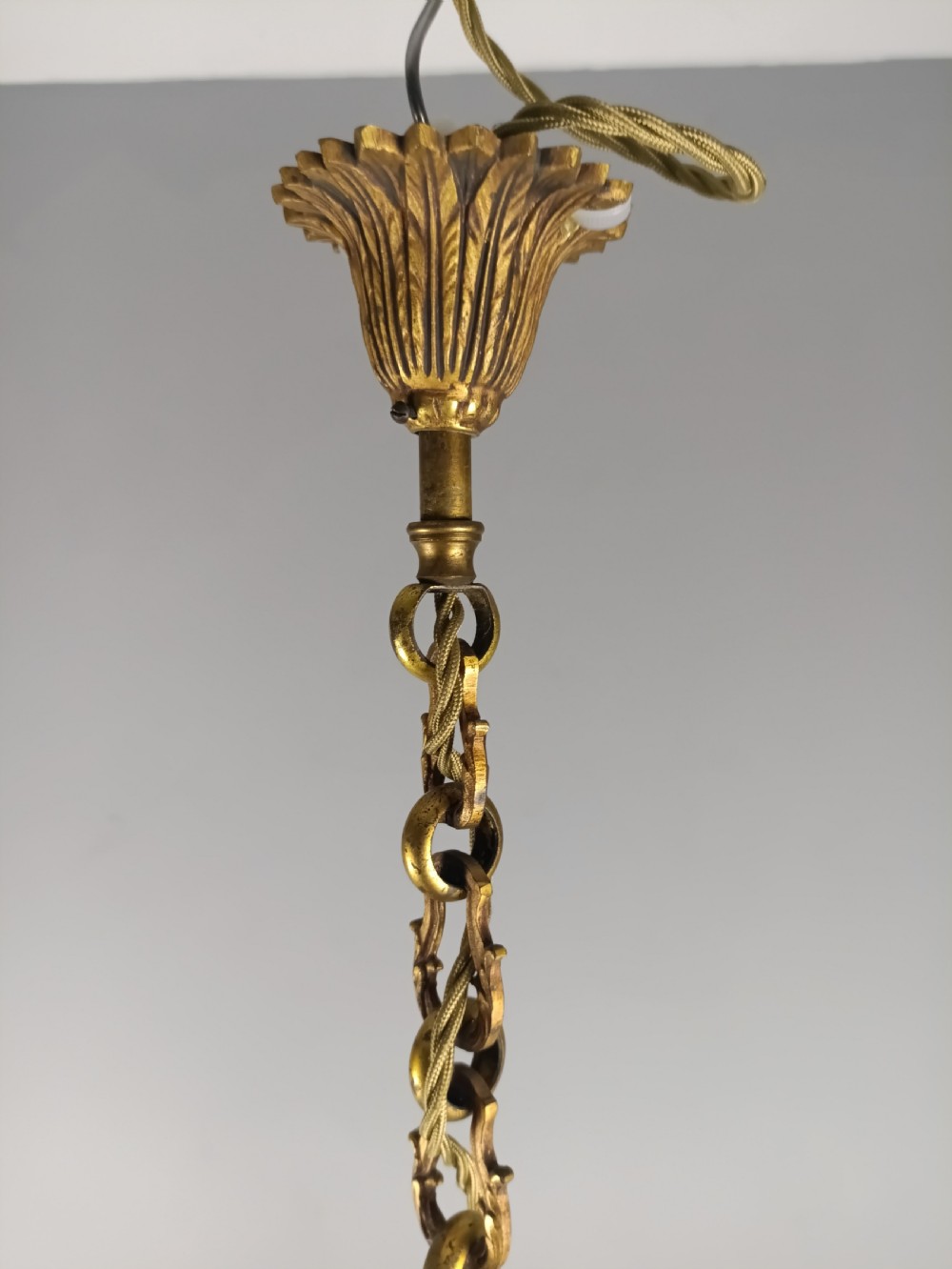 A French four-arm gilt bronze chandelier featuring acanthus leaf castings, white candle sleeves, and a suspended central chain. View XIII