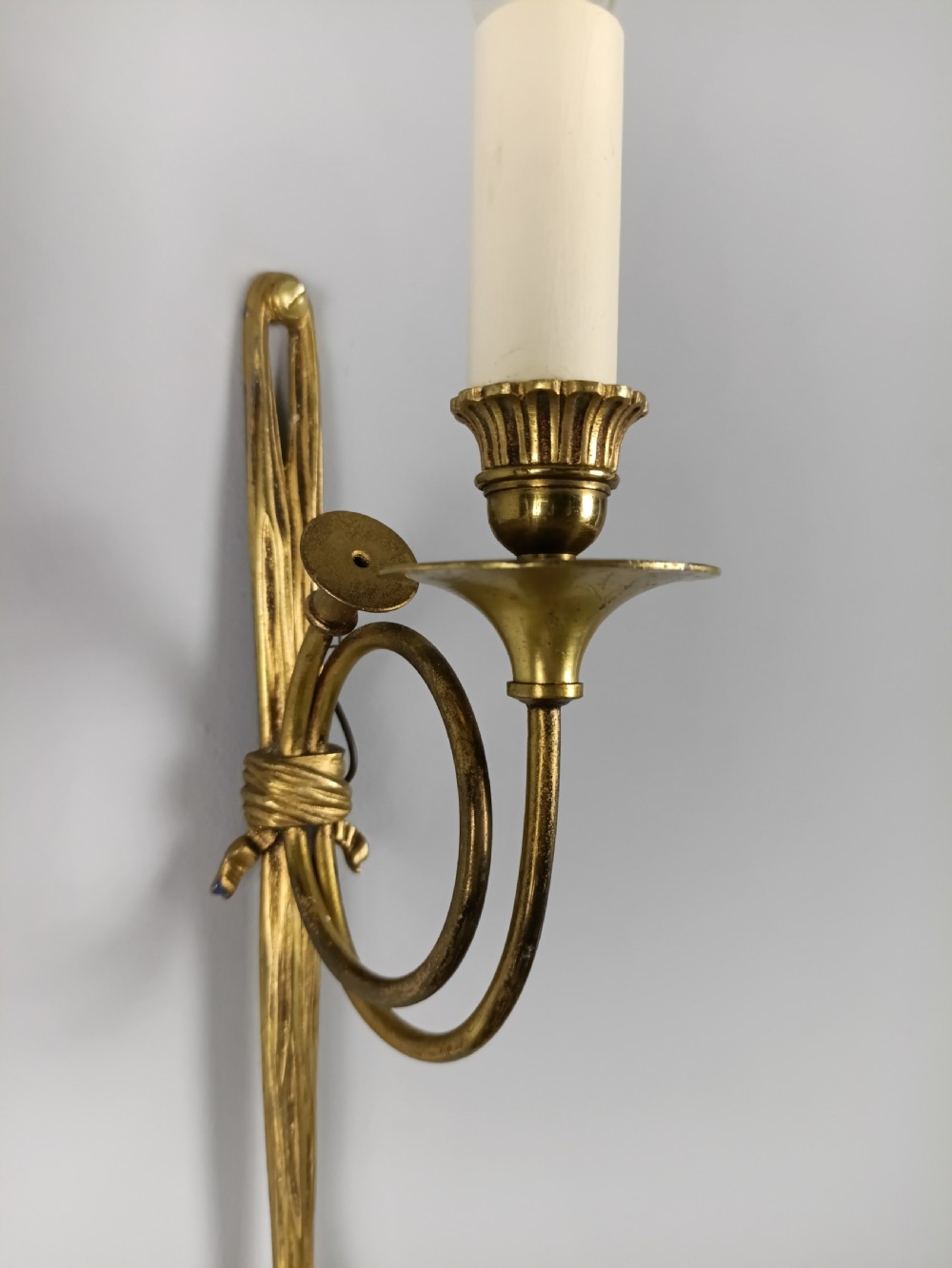 A single-arm French antique Louis XVI style wall sconce crafted from gilded brass with a horn motif arm and a white candle sleeve. View III