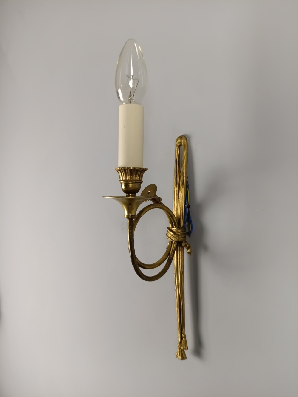A single-arm French antique Louis XVI style wall sconce crafted from gilded brass with a horn motif arm and a white candle sleeve. View VI