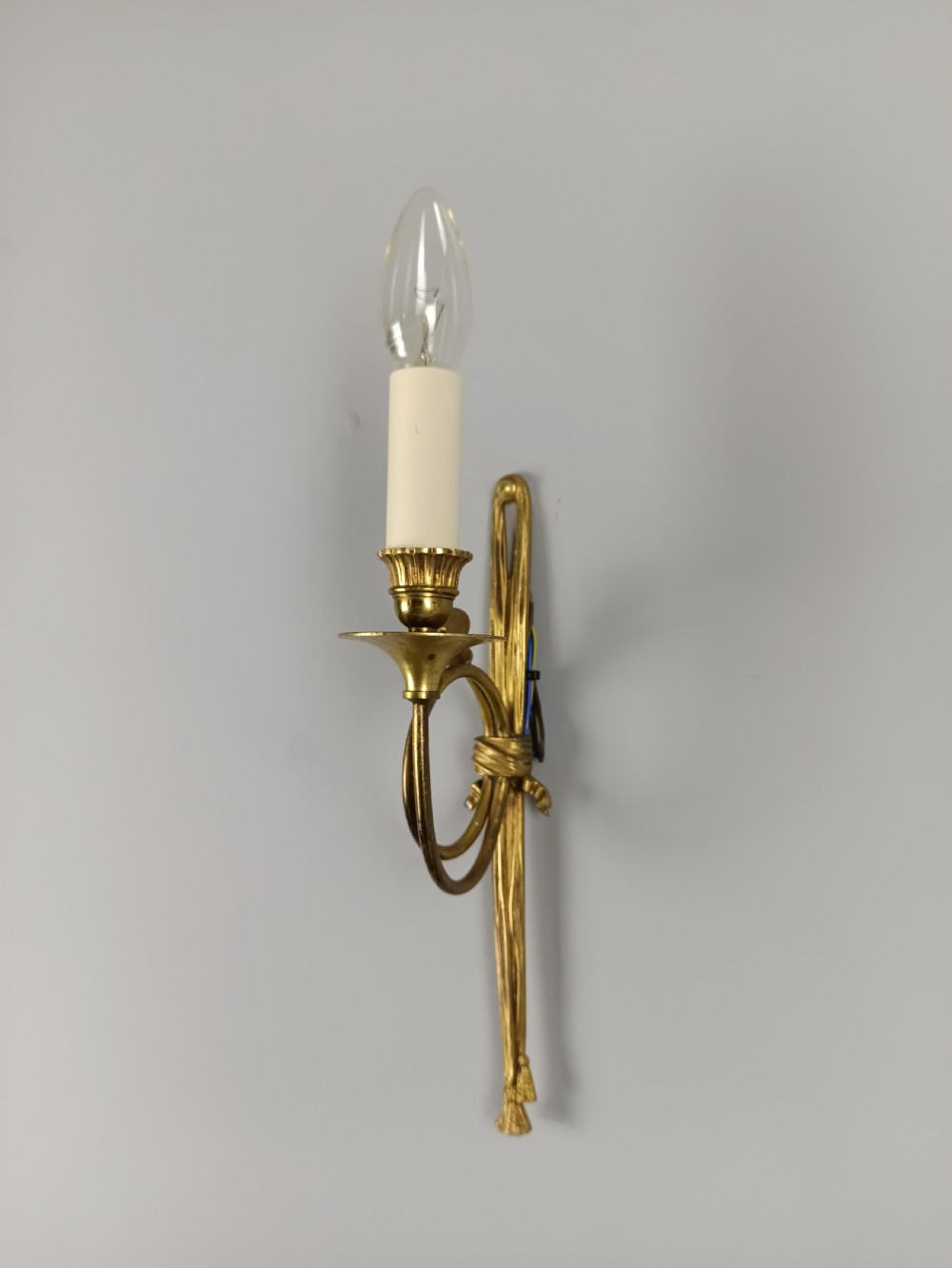 A single-arm French antique Louis XVI style wall sconce crafted from gilded brass with a horn motif arm and a white candle sleeve. View VII