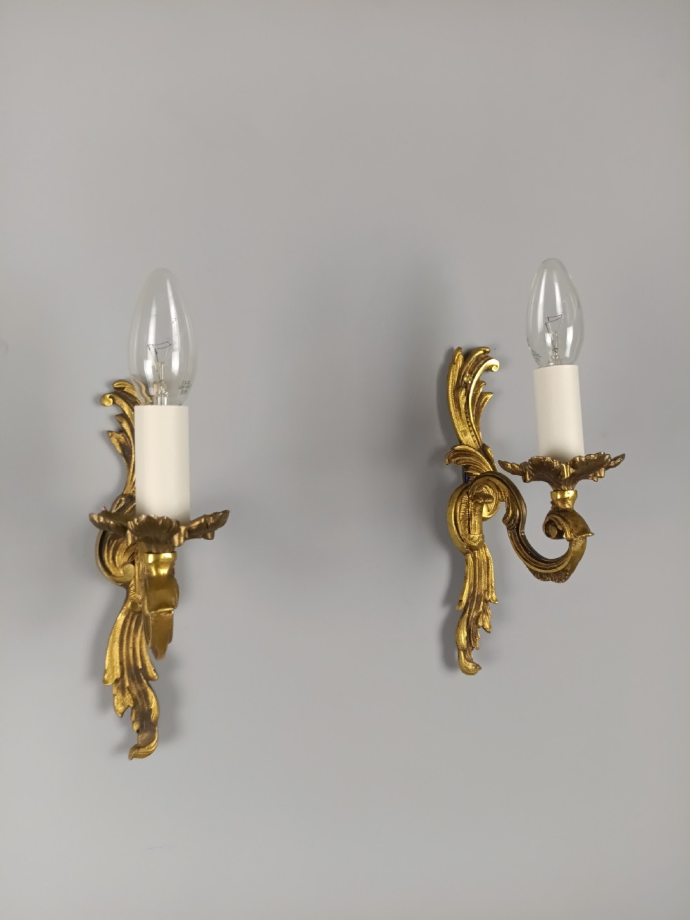 A pair of French Rococo style gilded bronze single-arm wall sconces featuring acanthus leaf scrollwork and candle-form sockets. View II