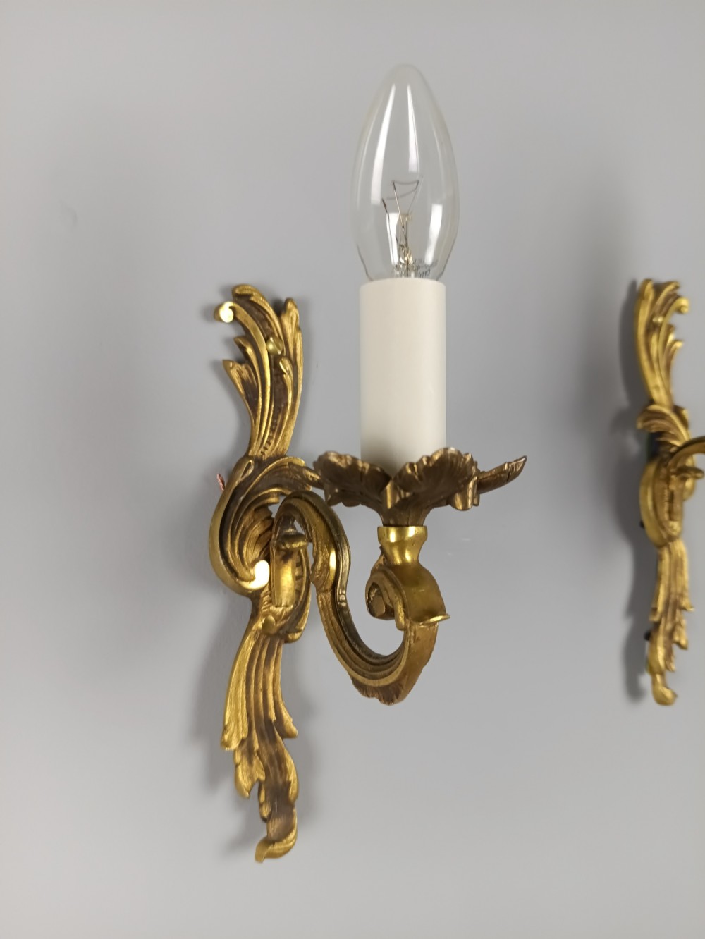 A pair of French Rococo style gilded bronze single-arm wall sconces featuring acanthus leaf scrollwork and candle-form sockets. View IV
