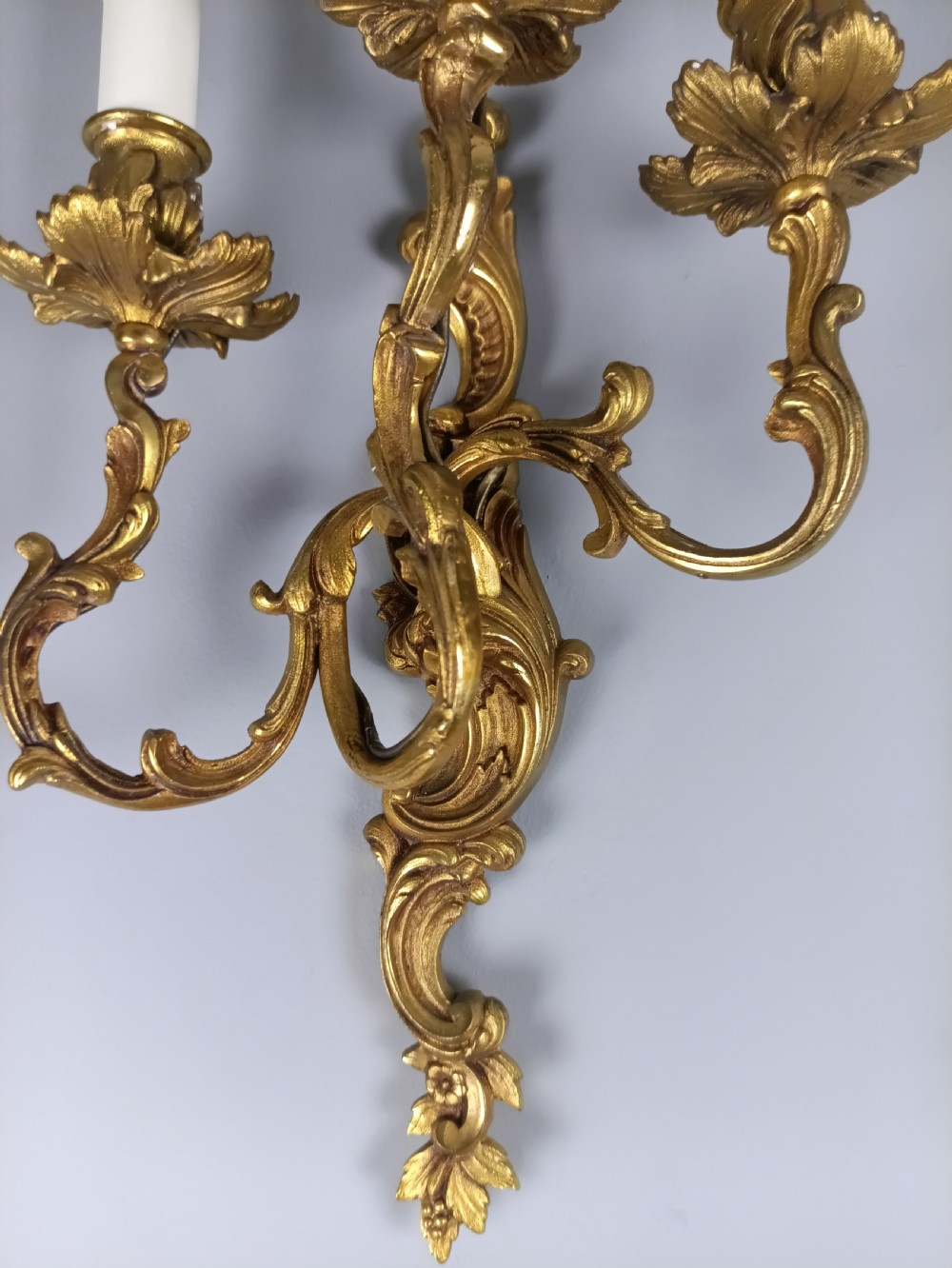 A pair of French Rococo style gilded bronze wall lights featuring three scrolling foliate arms and leaf motifs. View VI