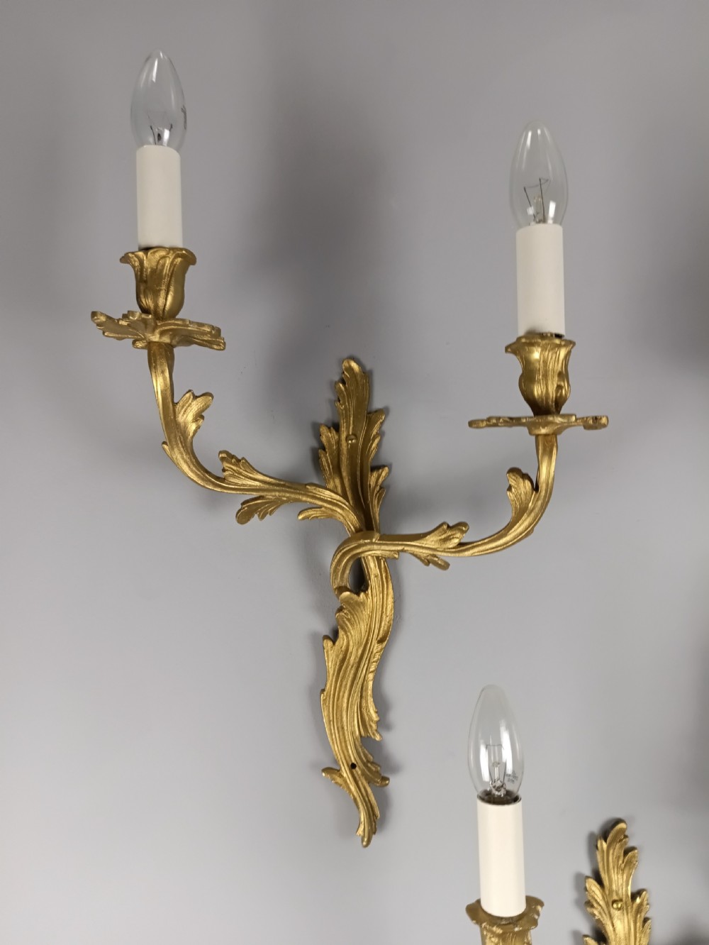 A set of four antique French Rococo style gilt bronze wall lights featuring twin curving foliate arms and acanthus leaf backplates. View II