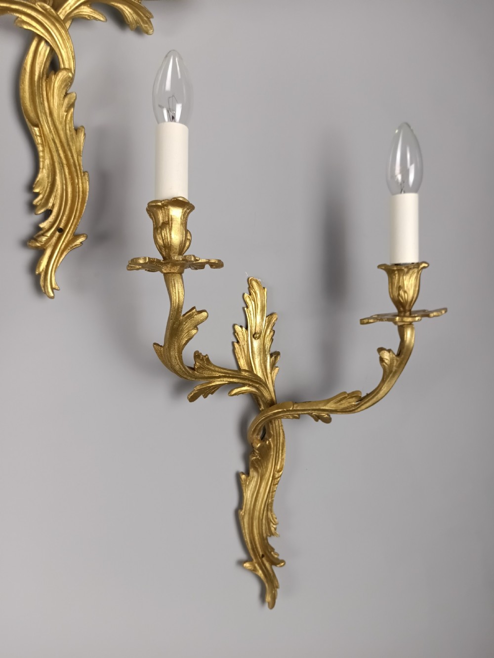A set of four antique French Rococo style gilt bronze wall lights featuring twin curving foliate arms and acanthus leaf backplates. View IV