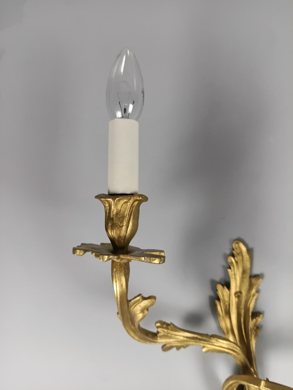 A set of four antique French Rococo style gilt bronze wall lights featuring twin curving foliate arms and acanthus leaf backplates. View VI