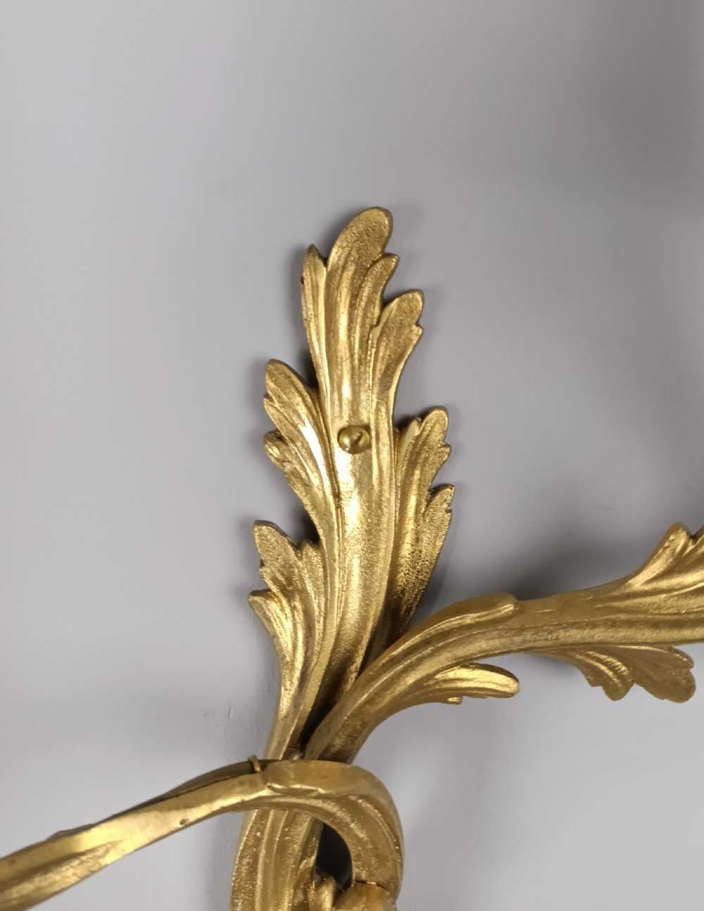 A set of four antique French Rococo style gilt bronze wall lights featuring twin curving foliate arms and acanthus leaf backplates. View VII