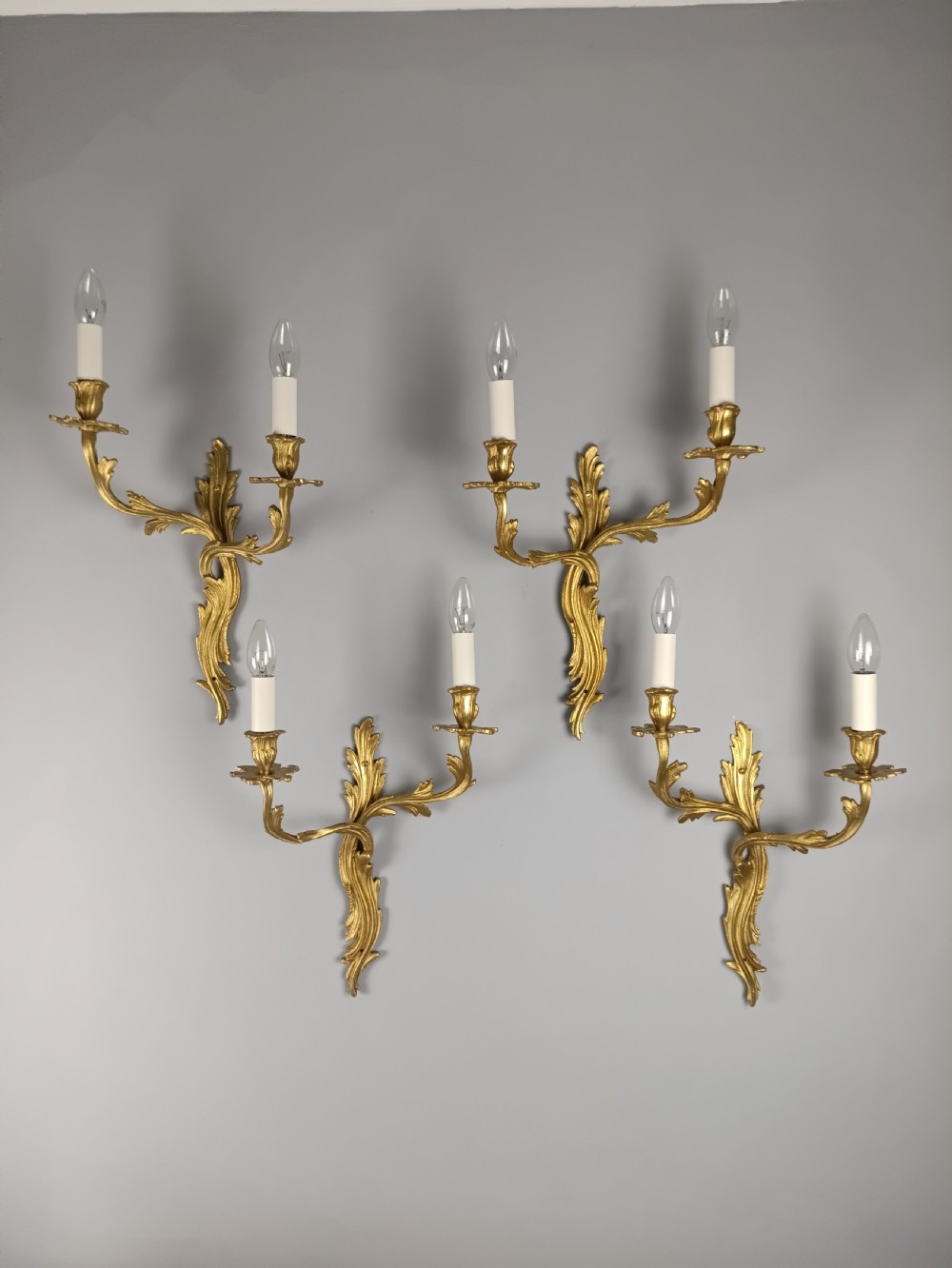 A set of four antique French Rococo style gilt bronze wall lights featuring twin curving foliate arms and acanthus leaf backplates. View IX