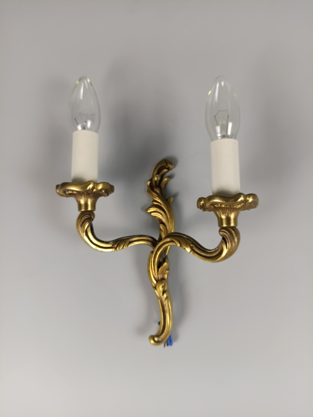 An antique French twin-arm gilt brass wall light featuring cast acanthus leaf scrolling and faux candle sleeves. View VI
