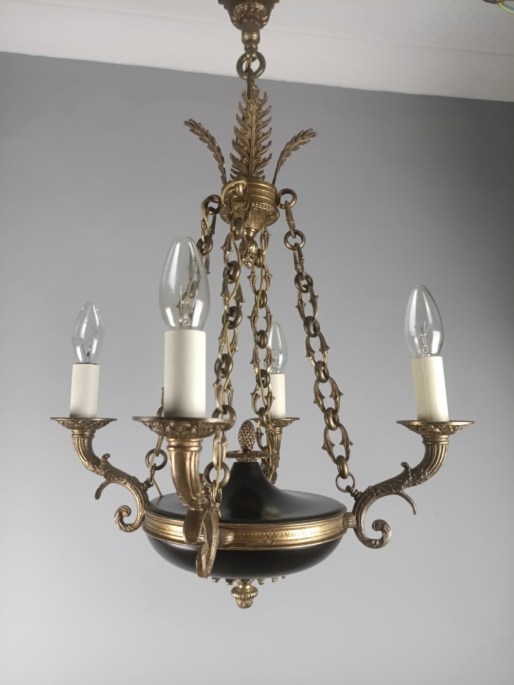 A French Empire four-light chandelier with a dark patinated central bowl suspended by decorative brass chains and acanthus leaf motifs. View II