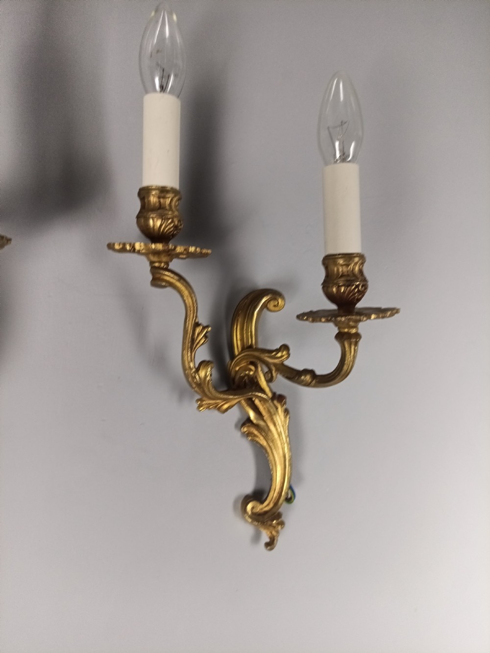 A pair of French gilt brass two-arm wall sconces featuring scrolling acanthus leaf details and candle-style bulb holders. View II