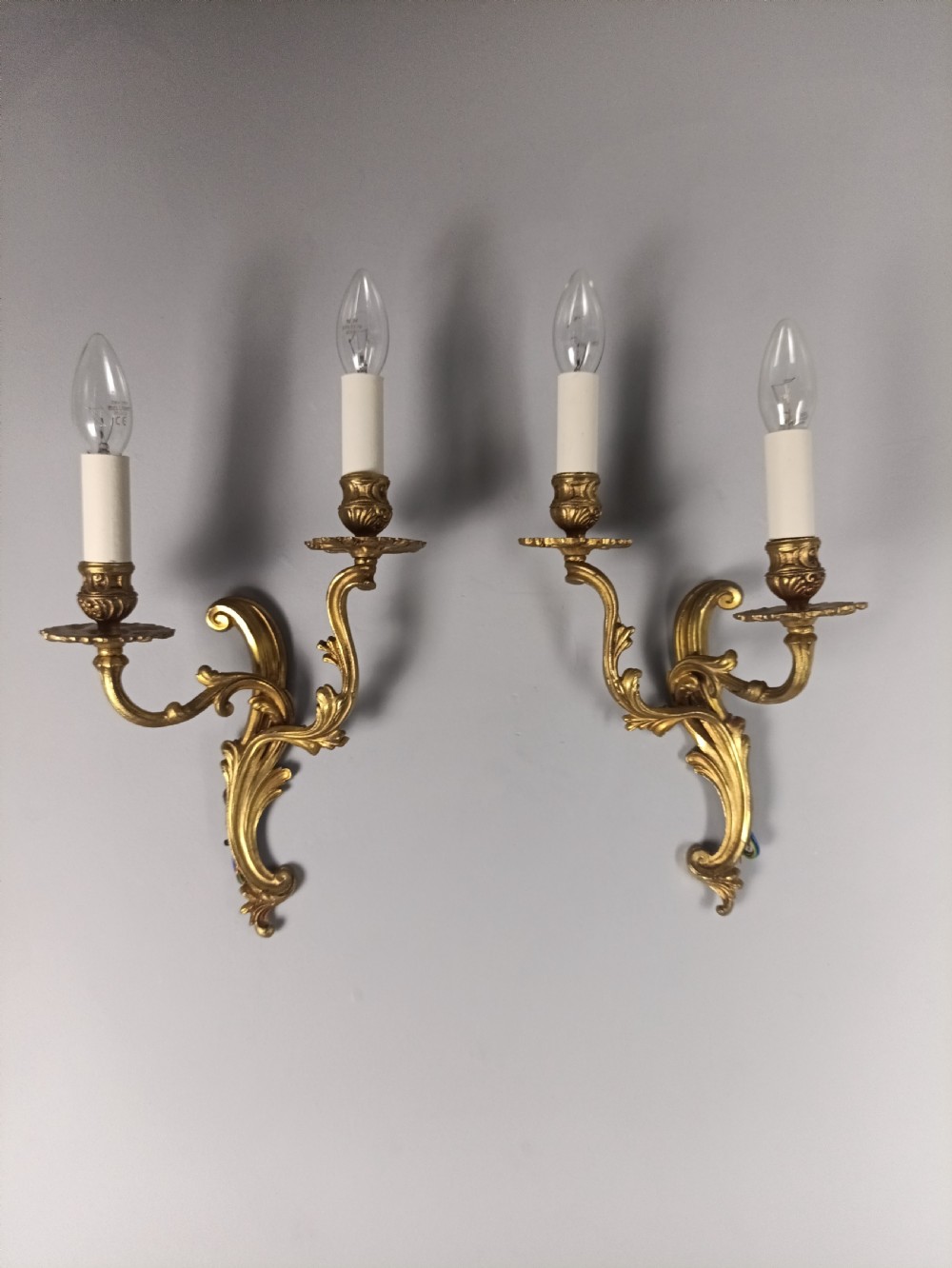 A pair of French gilt brass two-arm wall sconces featuring scrolling acanthus leaf details and candle-style bulb holders. View III