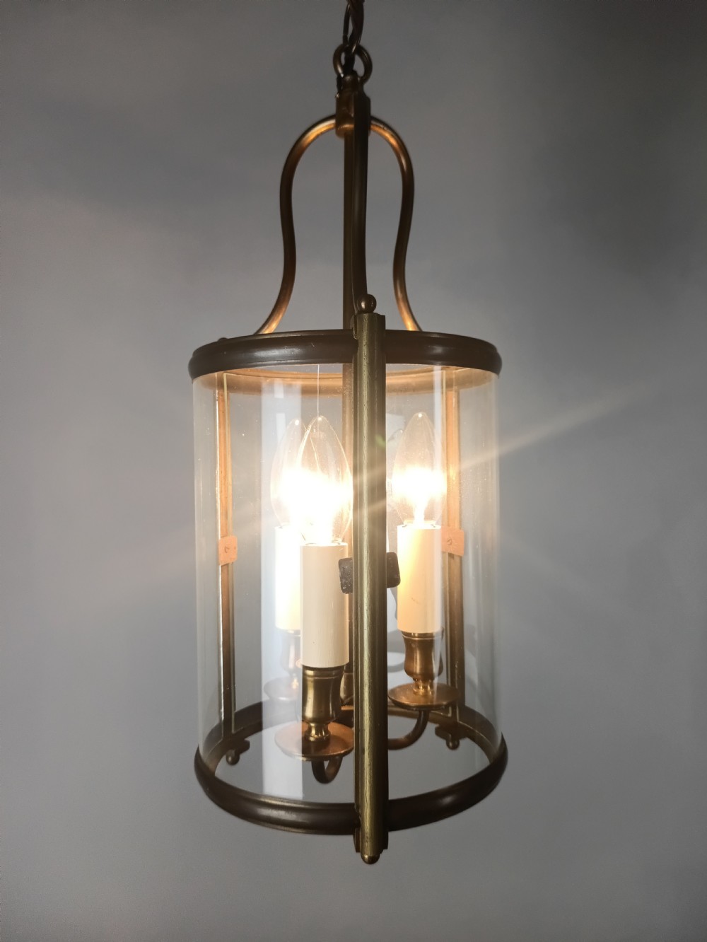 A cylindrical gilded brass hall lantern featuring curved clear glass panels and an internal three-light candle cluster. View XI