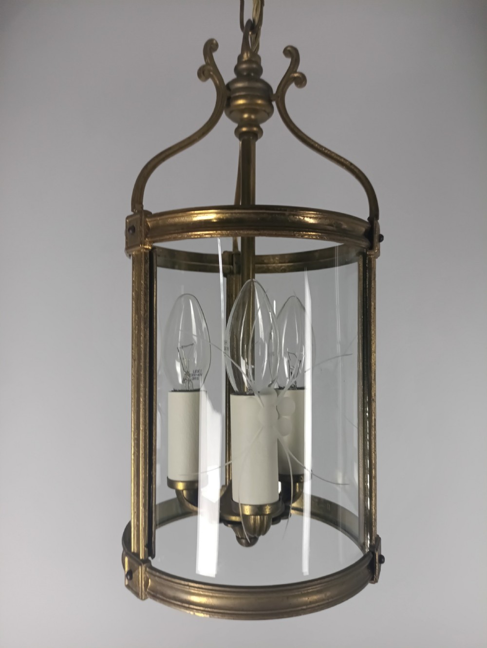 A cylindrical French gilt brass hall lantern with etched curved glass panels housing a three-bulb candle fitting.