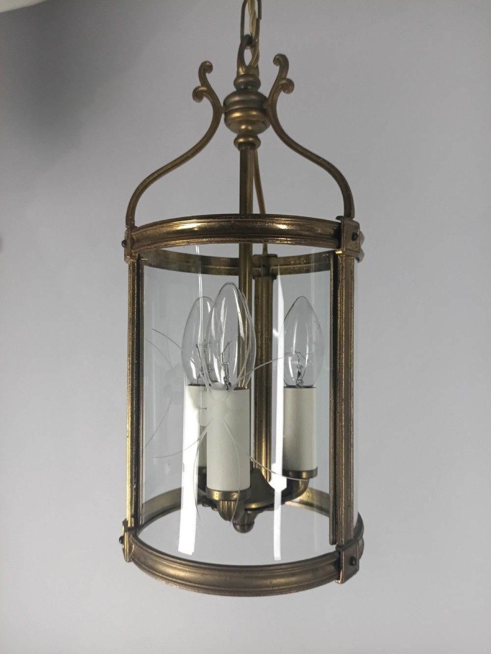 A cylindrical French gilt brass hall lantern with etched curved glass panels housing a three-bulb candle fitting. View II