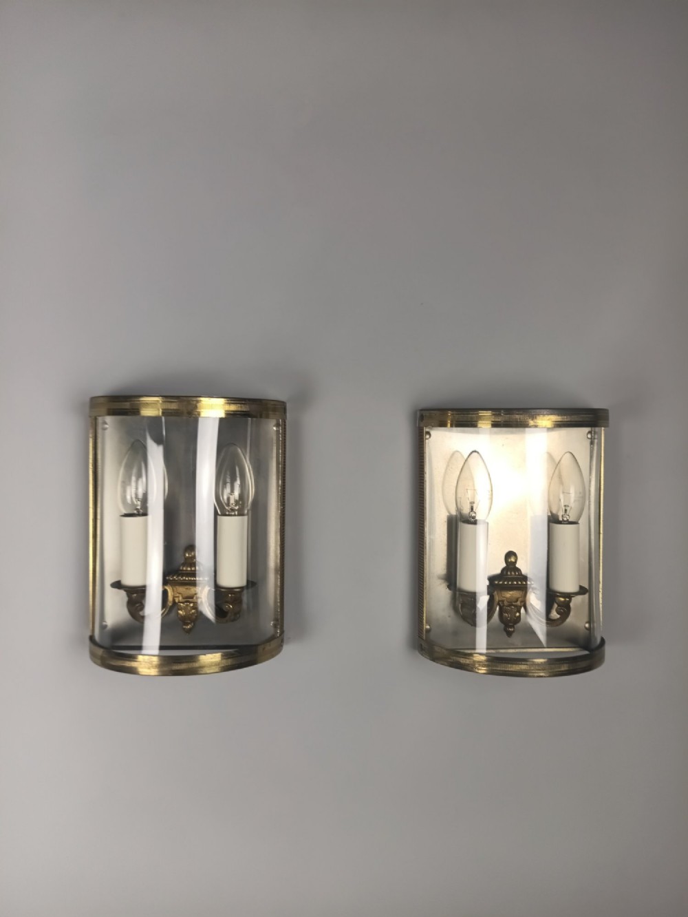 A pair of French gilt brass half-lantern wall lights featuring curved clear glass panels and twin candle-style sockets. View II