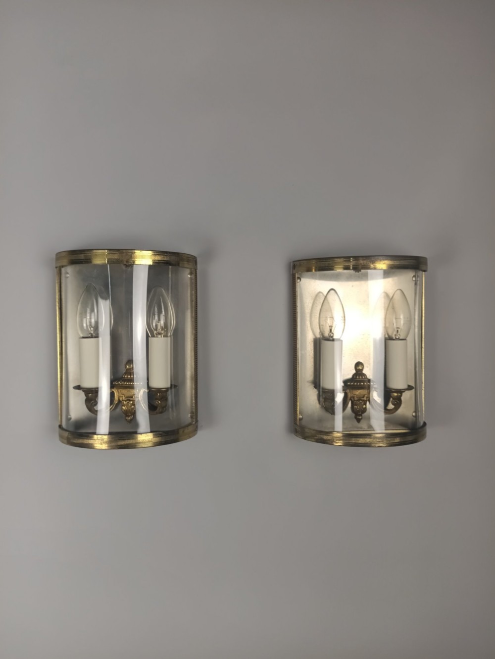 A pair of French gilt brass half-lantern wall lights featuring curved clear glass panels and twin candle-style sockets. View III