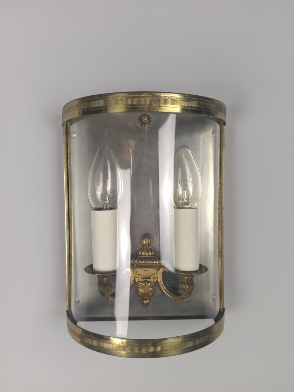 A pair of French gilt brass half-lantern wall lights featuring curved clear glass panels and twin candle-style sockets. View IV