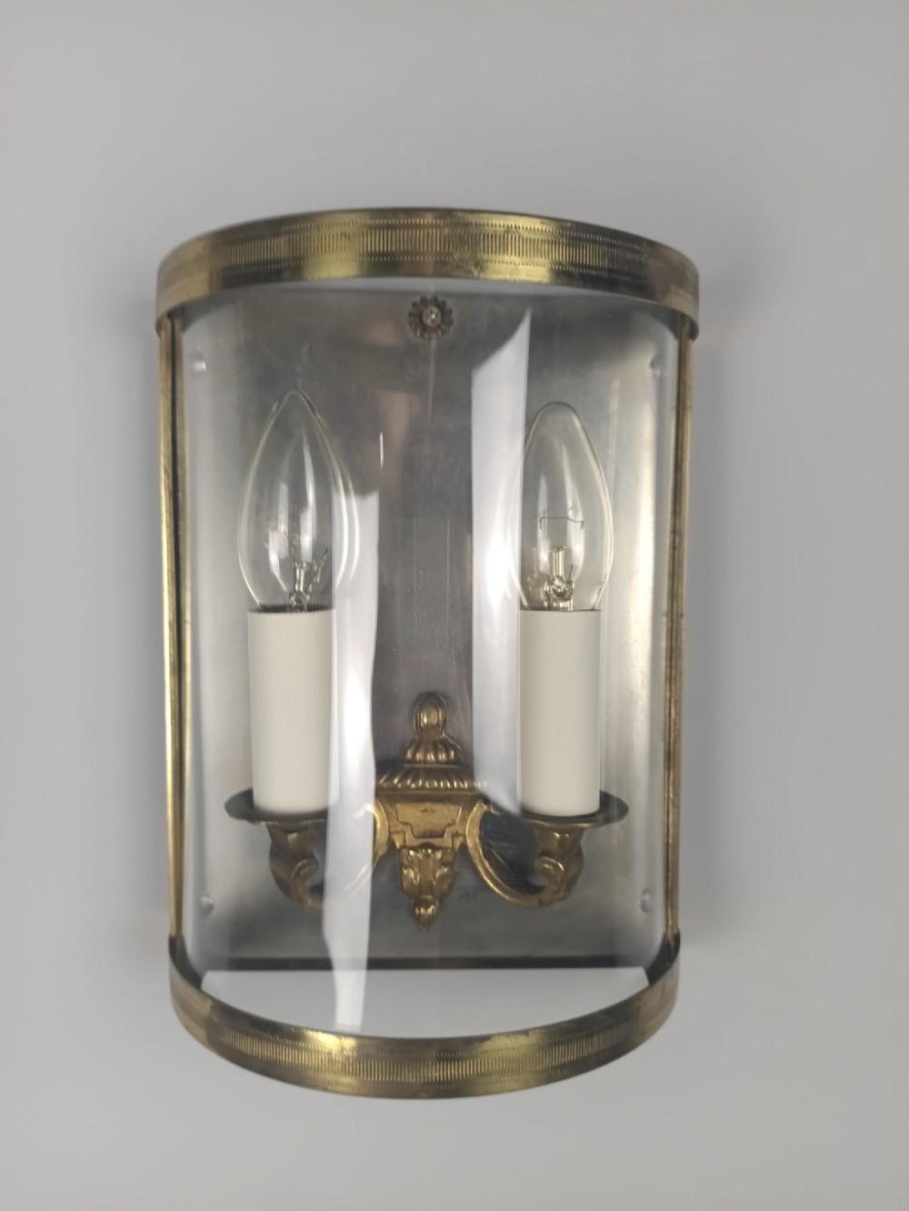 A pair of French gilt brass half-lantern wall lights featuring curved clear glass panels and twin candle-style sockets. View VII