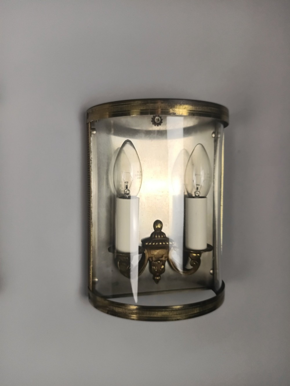 A pair of French gilt brass half-lantern wall lights featuring curved clear glass panels and twin candle-style sockets. View VIII