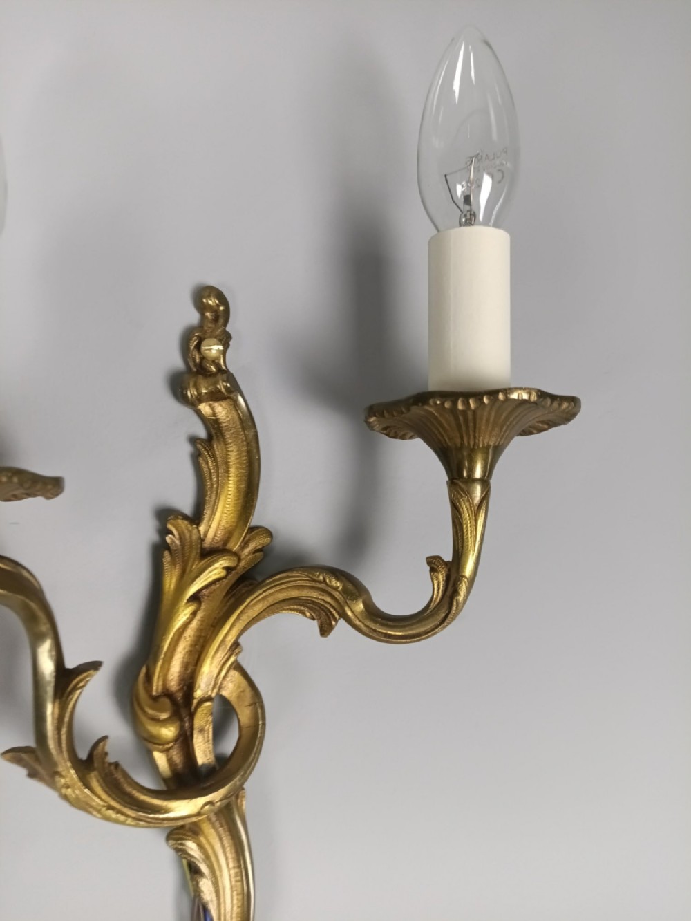 A set of three French gilded bronze twin-arm wall lights with ornate foliage scrolling and candle-style sockets. View VII